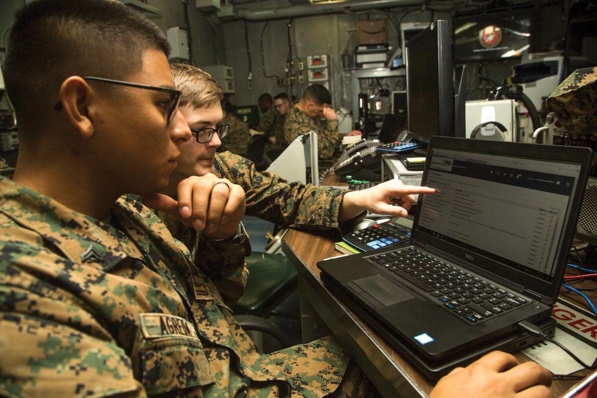 Two Marines sitting while working on a laptop computer