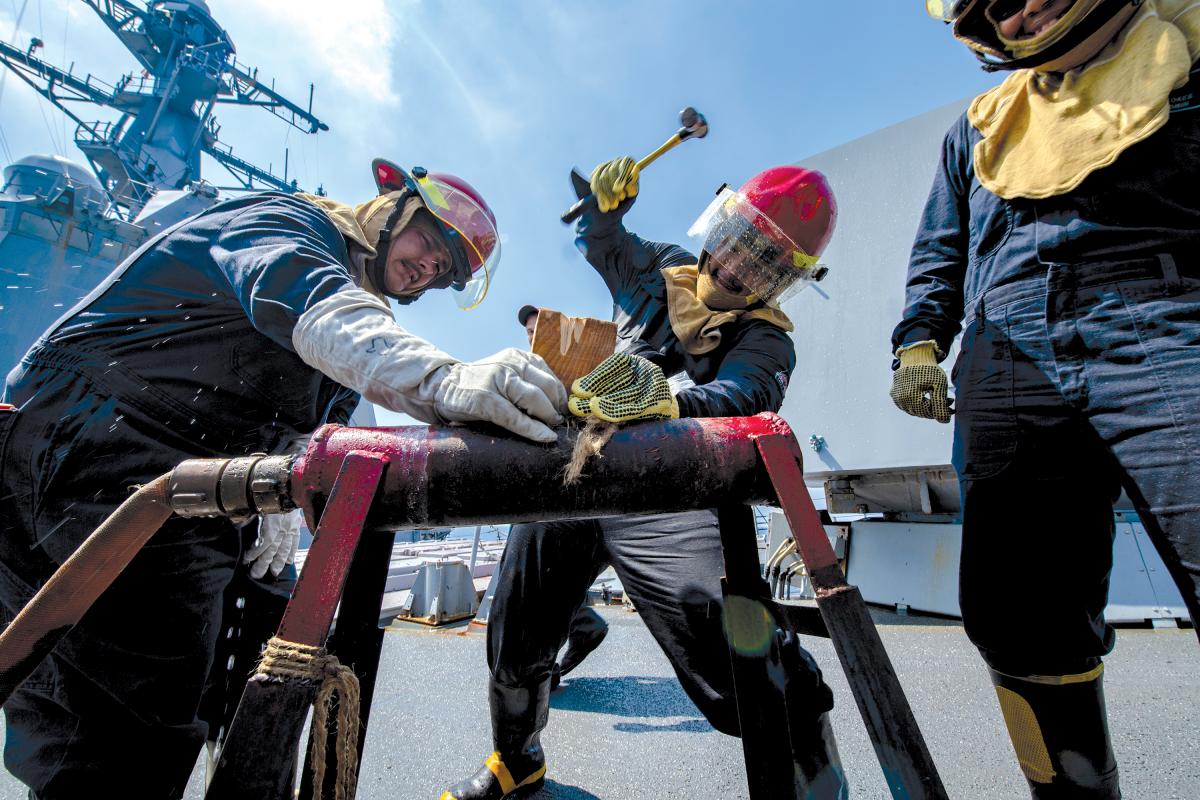 Sailors participate in a pipe patching drill during damage control olympics
