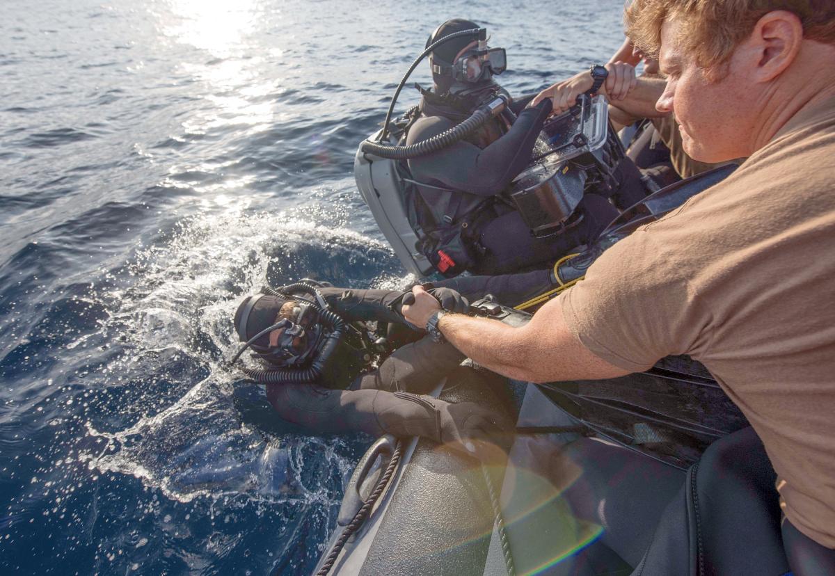 Sailors are lowered into the water during Mark 16 dive training