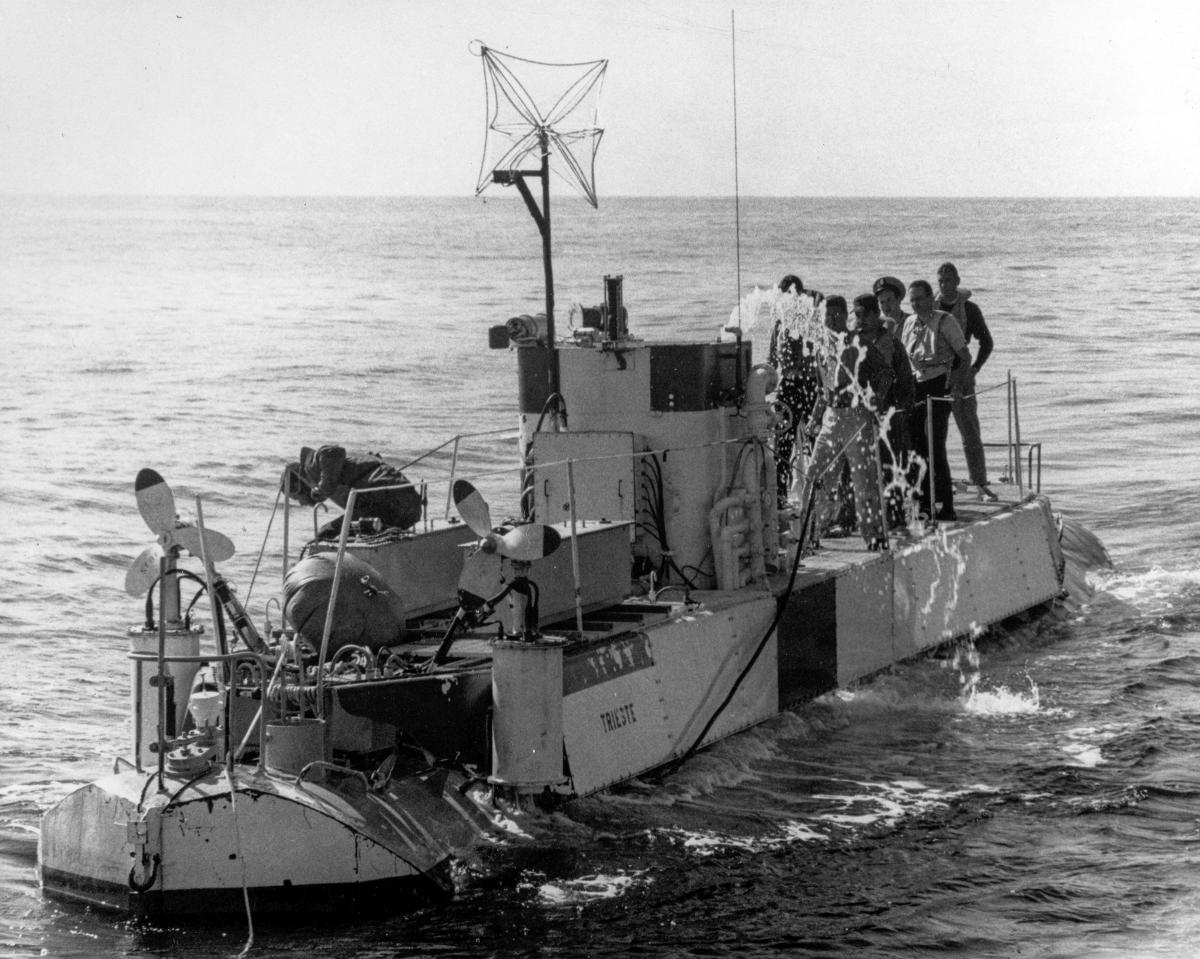 The Trieste (DSV-0) surfaces during search operations for the USS Thresher (SSN-593), blowing water out of the entrance changer to permit observers and the pilot to climb out.