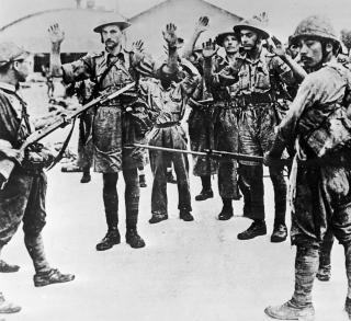Japanese soldiers guard a group of Singapore’s defeated defenders.
