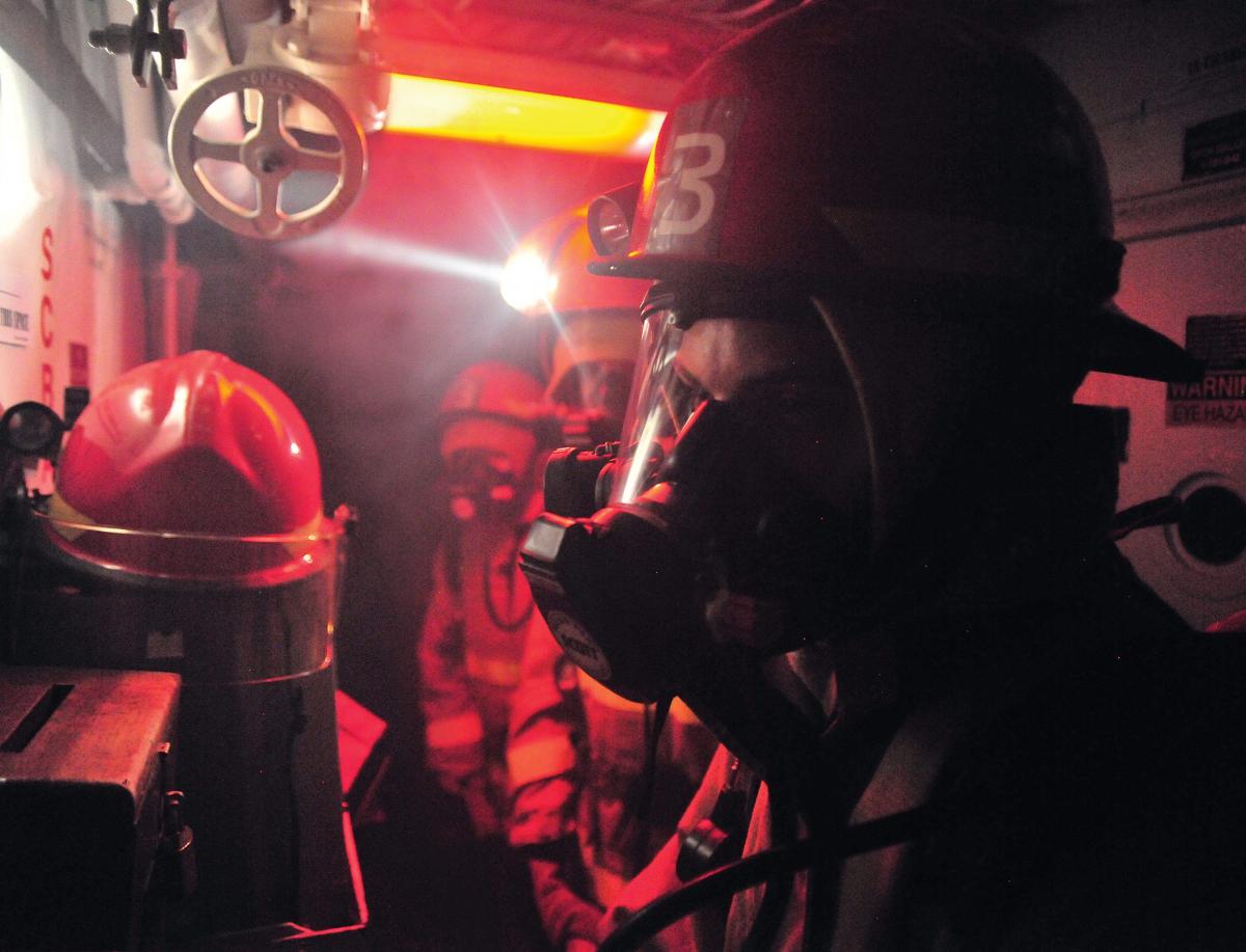 Sailors prepare to enter a smoke-filled space during a general quarters drill