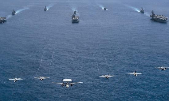 Aircraft from Carrier Air Wing 9 fly over the aircraft carrier USS Abraham Lincoln (CVN-72, front left), Tripoli (LHA-7, front center), Ronald Reagan (CVN-76, front right), Mobile Bay (CG-53, middle left), Benfold (DDG-65, middle center), Antietam (CG-54, middle right), Spruance (DDG-111, back left), and Fitzgerald  (DDG-62, back right) as they sail in formation in the Philippine Sea during Valiant Shield 2022.