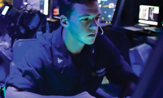 Navy cyber technician sitting at a terminal.