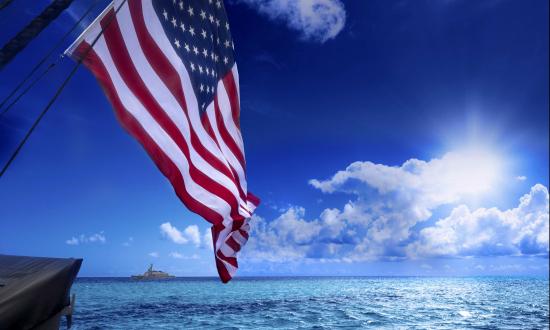 Banner showing closeup of American Flag in front of a sunlit sea