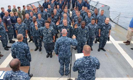 Cmdr. Stephen Fuller, commanding officer of the guided-missile frigate USS Nicholas (FFG 47), advances three officers and 27 new petty officers during a promotion and advancement ceremony. 