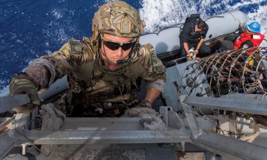 Coast Guard law enforcement detachments (LEDets) deploy with U.S. Navy strike groups as part of the Oceania Maritime Security Initiative. Here, a LEDet member climbs down to a rigid-hull inflatable boat to conduct a boarding mission.