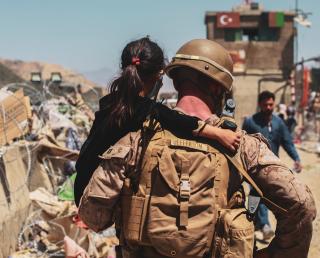 A Marine carries a child to be processed for evacuatio